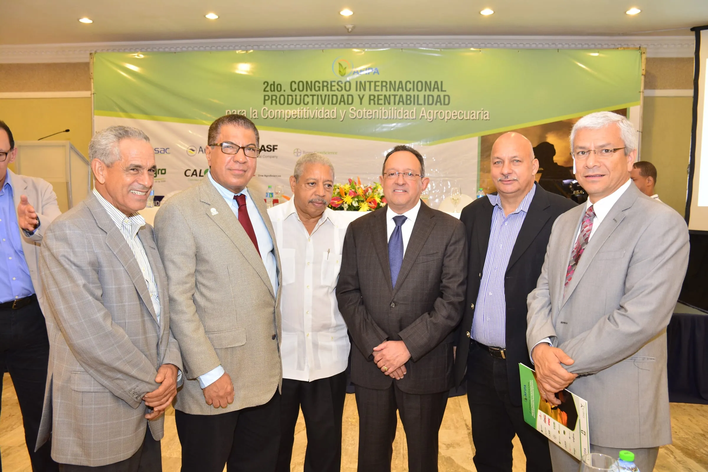 Seis organizadores y expositores del segundo congreso posan juntos delante del banner del evento